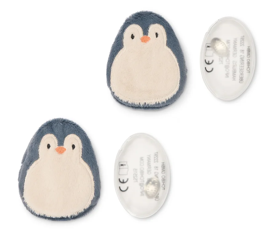 Zwei plüschige Pinguin-förmige Objekte in Dunkelblau und Beige, jeweils neben einer transparenten ovalen Scheibe mit Text und CE-Zeichen.