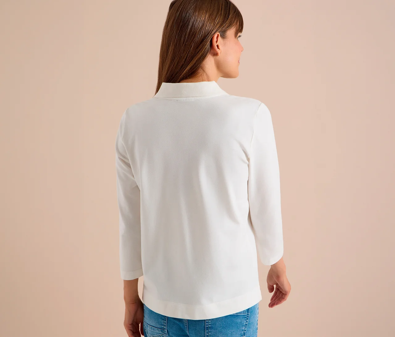 Frau von hinten, die ein weißes CECIL 3/4-Poloshirt und blaue Jeans trägt.