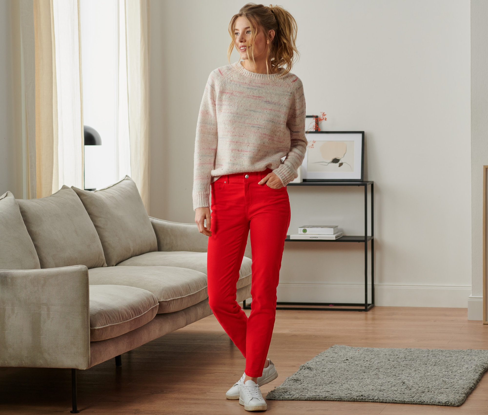 Frau steht im Wohnzimmer und trägt Coloured Denim.