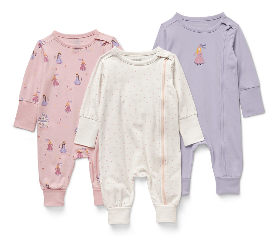 Drei Baby-Pyjamas mit Prinzessinnen-Motiv. Einer ist rosa mit Aufdruck, einer weiß mit Punkten und einer lila mit einem Prinzessinnenbild.