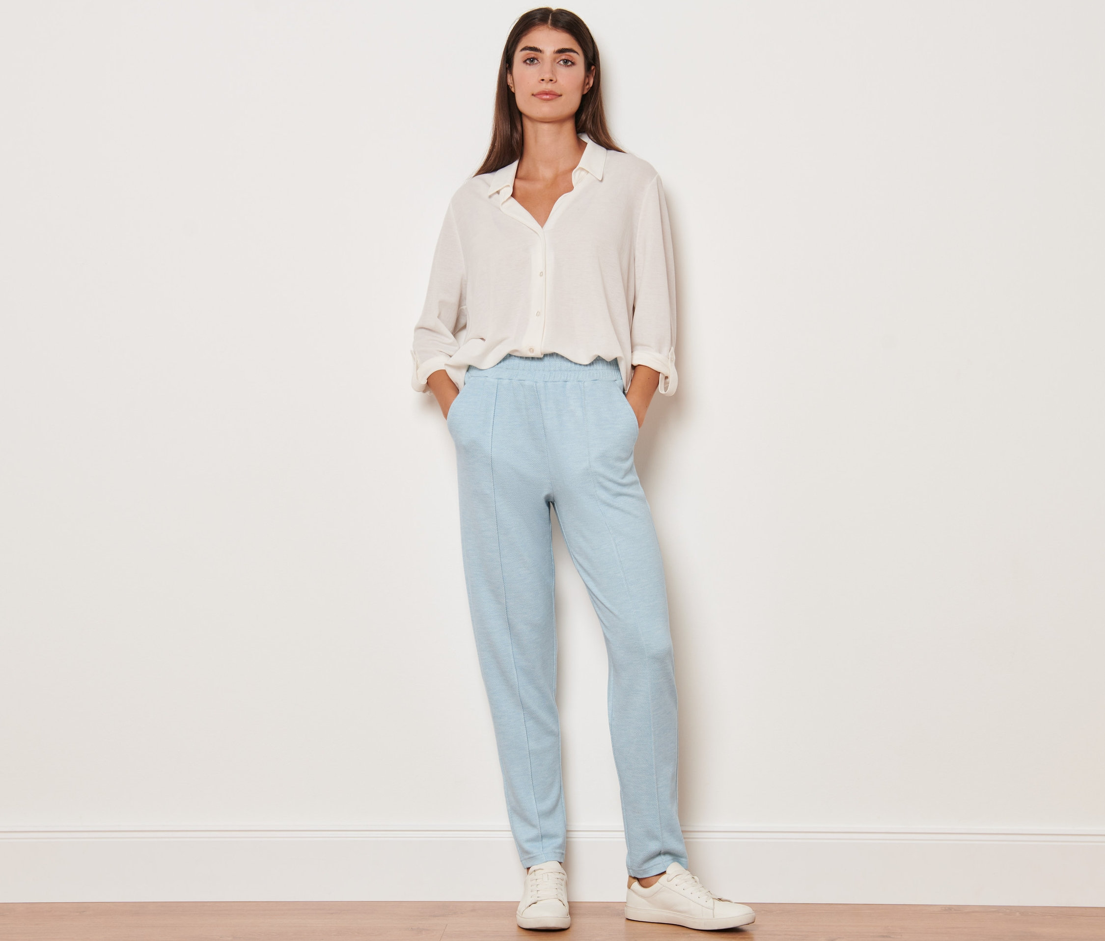 Eine Frau steht mit den Händen in den Taschen ihrer Joggpants mit Biese.