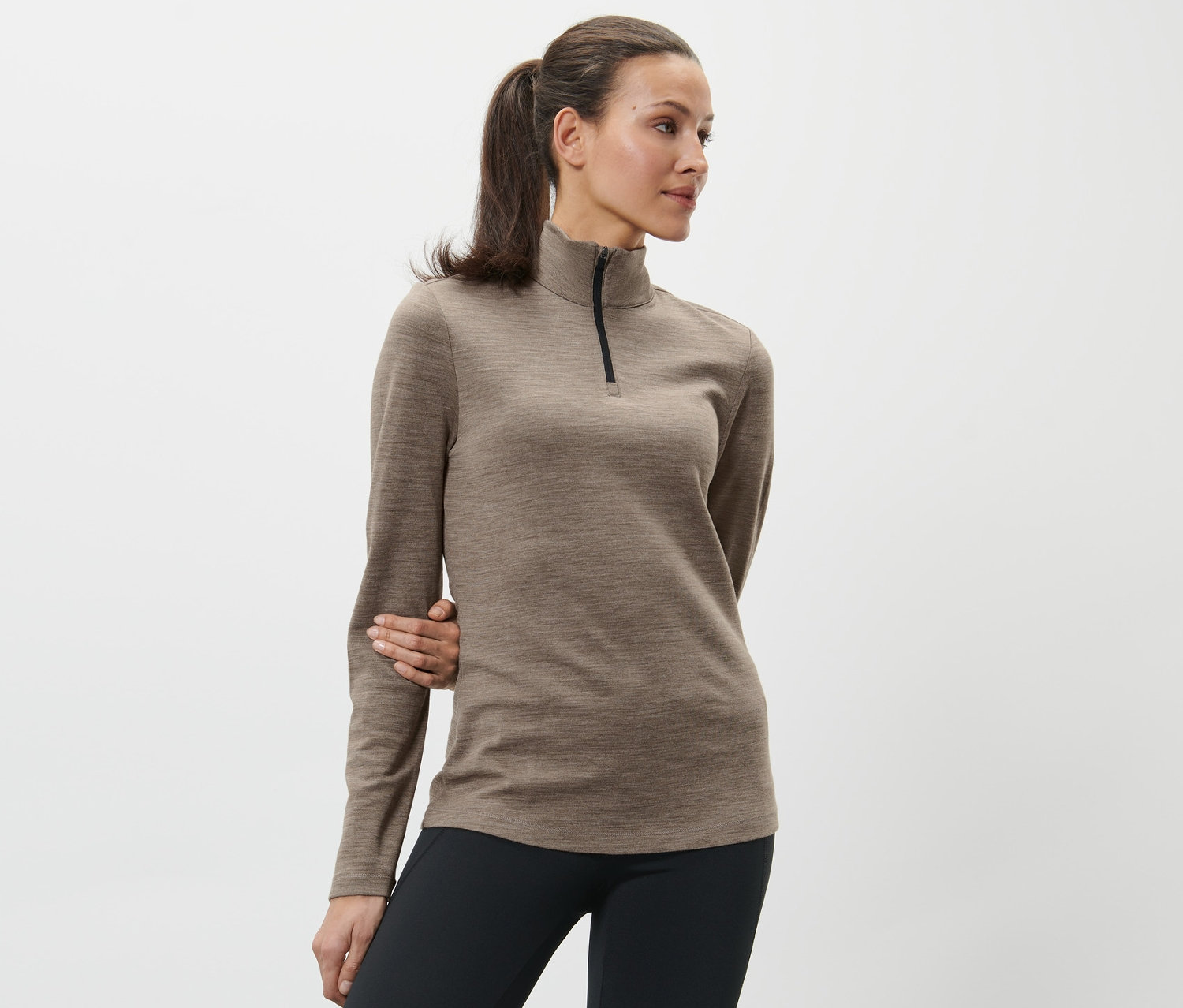 Frau posiert in braunem Shirt mit RWS-zertifizierter Wolle und schwarzen Leggings.