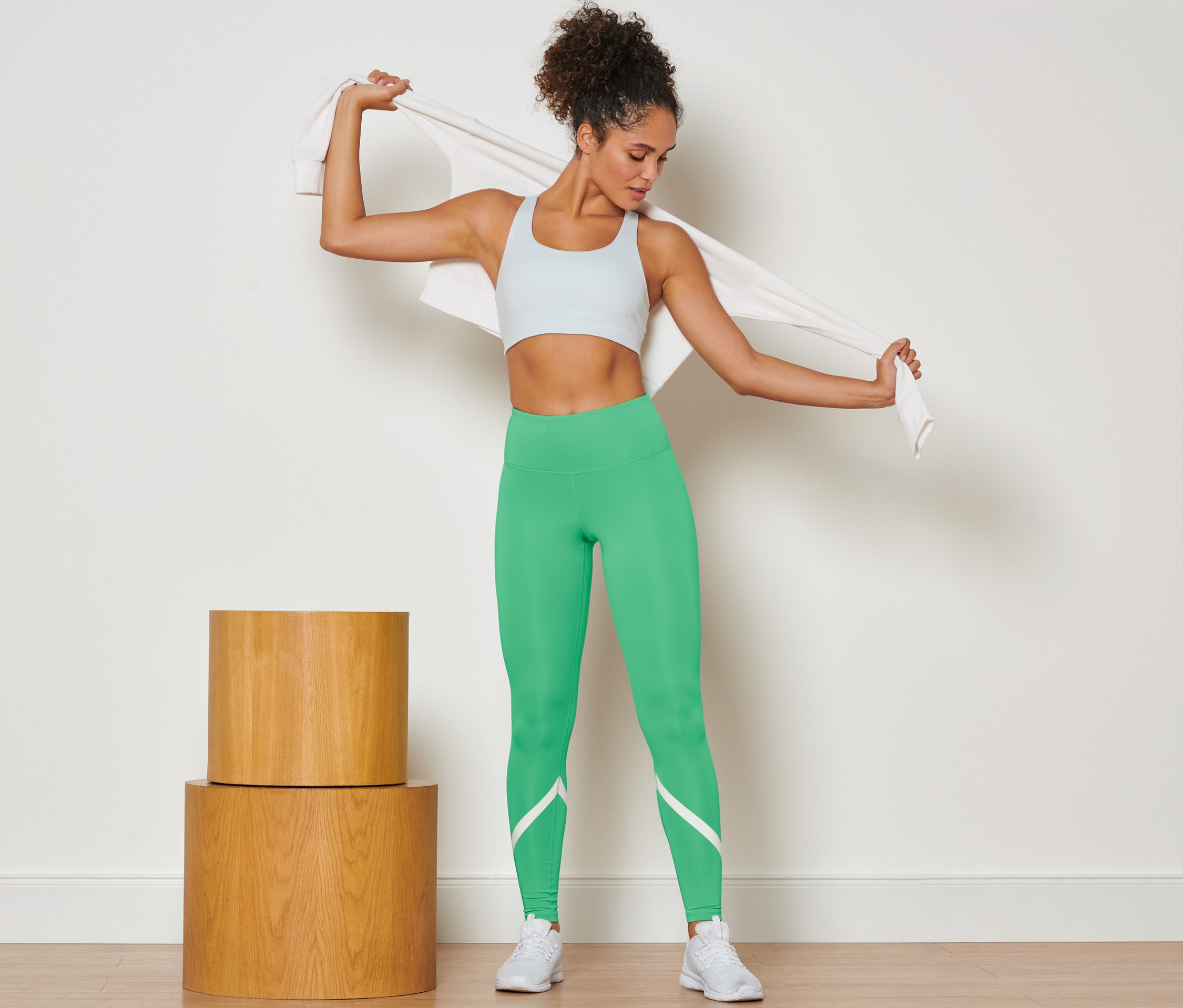 Frau legt sich ein Handtuch über die Schultern und trägt eine grüne Sporttight.