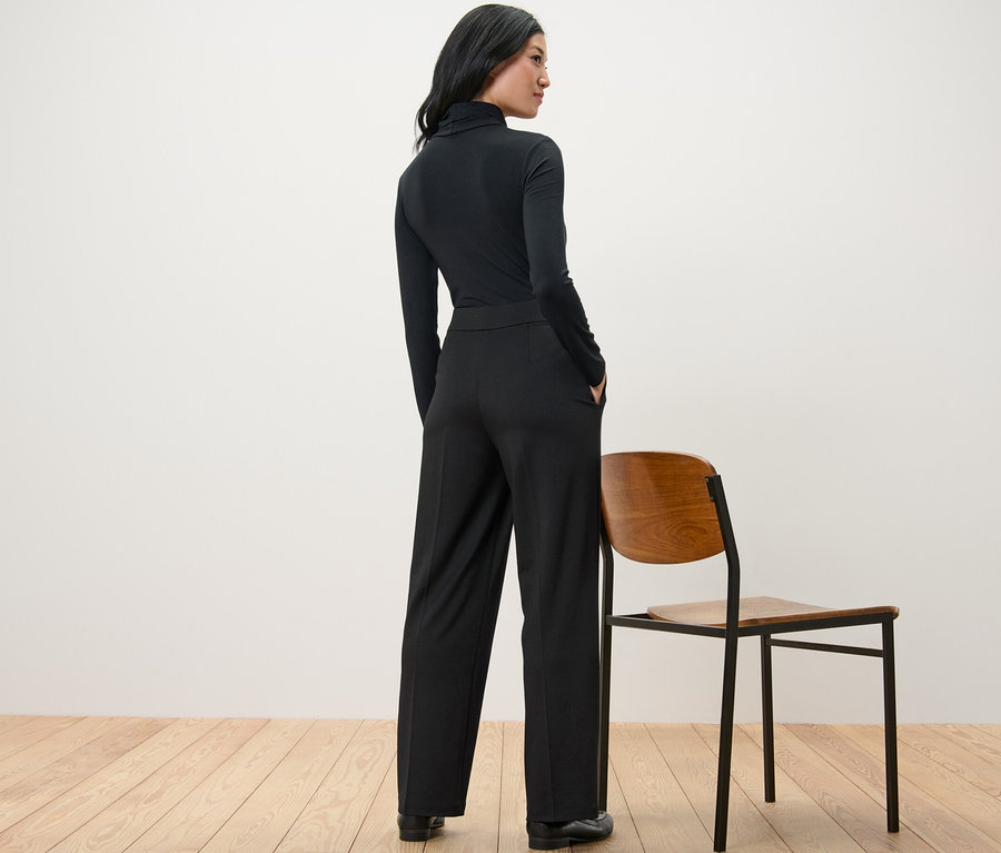 Frau steht mit dem Rücken zur Kamera und trägt eine schwarze Komfort-Jerseyhose.