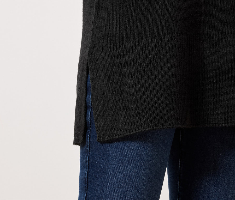 Schwarzer Pullover mit seitlichem Schlitz, getragen mit blauen Jeans.