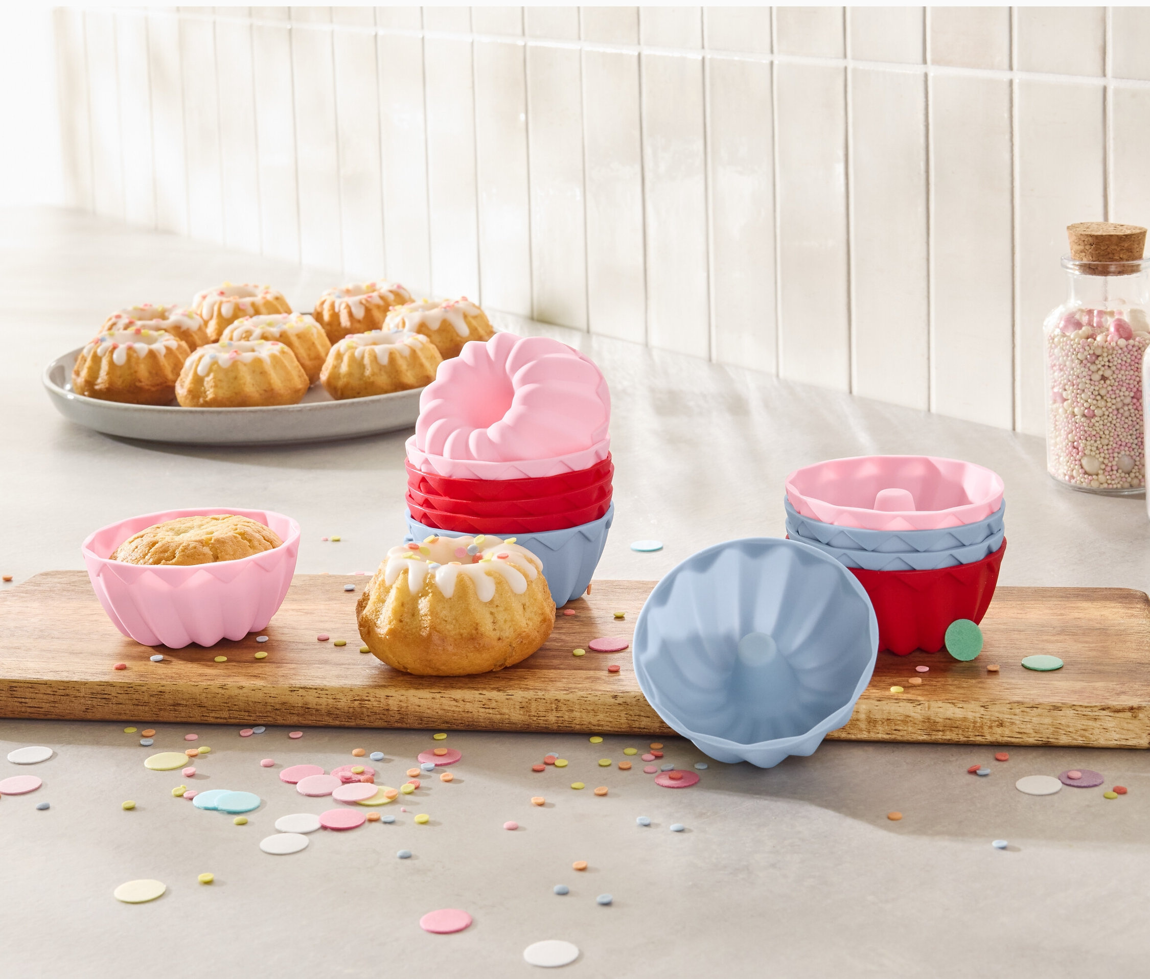 Mini-Gugelhupfe auf einem Teller und 12 Mini-Gugelhupfformen auf einem Holzbrett.