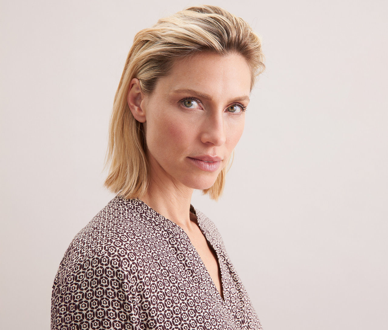 Porträt einer blonden Frau, die eine Seidensticker Tunika aus Viskose mit ecru-burgundy Alloverprint trägt.