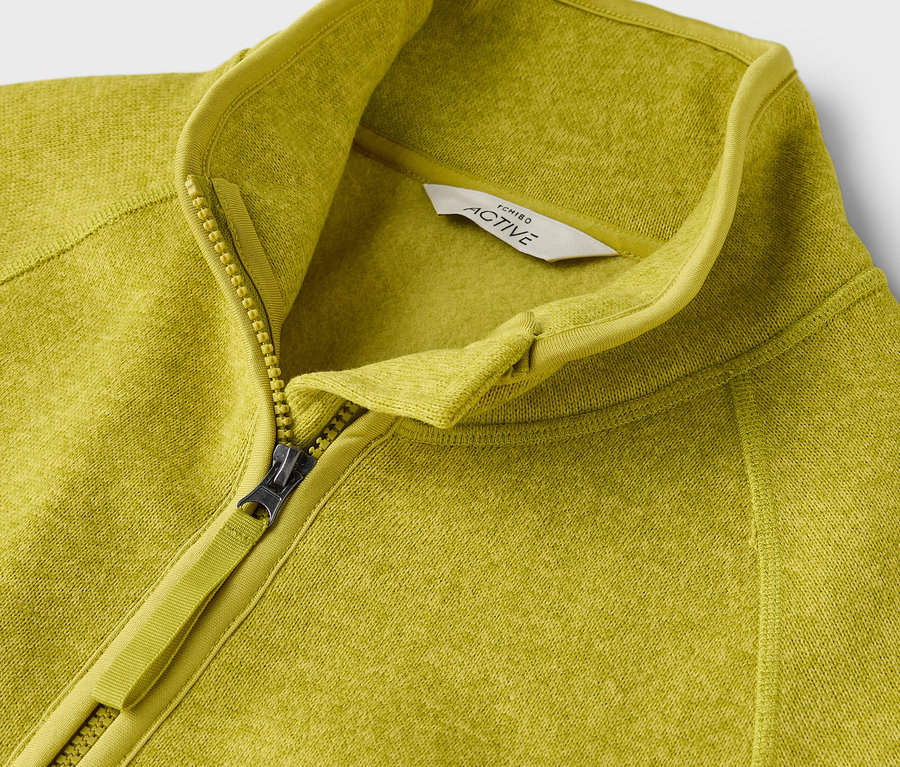 Detailaufnahme einer gelbgrünen Active-Fleecejacke mit Reißverschluss.