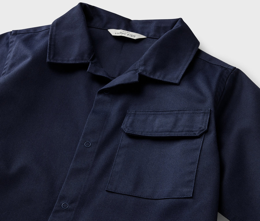 Detailansicht eines blauen Kinder-Overshirts mit kurzen Ärmeln und einer Tasche.