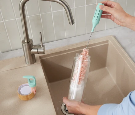Eine Frau reinigt eine Flasche mit der 3-in-1-Gläser-und-Flaschenspülbürste.