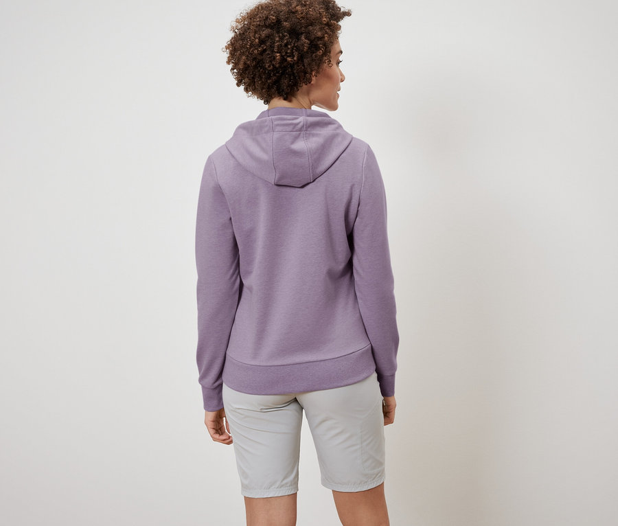 Rückansicht einer Frau mit lockigem Haar, die eine Sweatjacke und Shorts trägt.