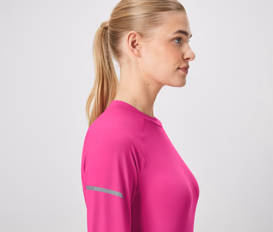 Profil einer Frau mit blonden, zum Pferdeschwanz gebundenen Haaren, die ein rosafarbenes Langarmshirt trägt.