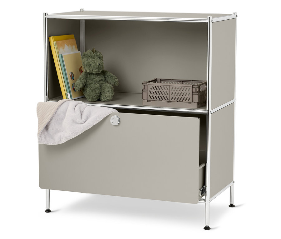 Ein graues Regal mit einem Teddybär, Büchern, einer grauen Kiste und einem weißen Handtuch.