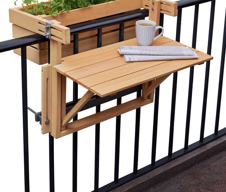 Pflanzkasten mit Kräutern und Klapptisch mit Zeitung und Tasse hängen an einem schwarzen Balkongeländer.