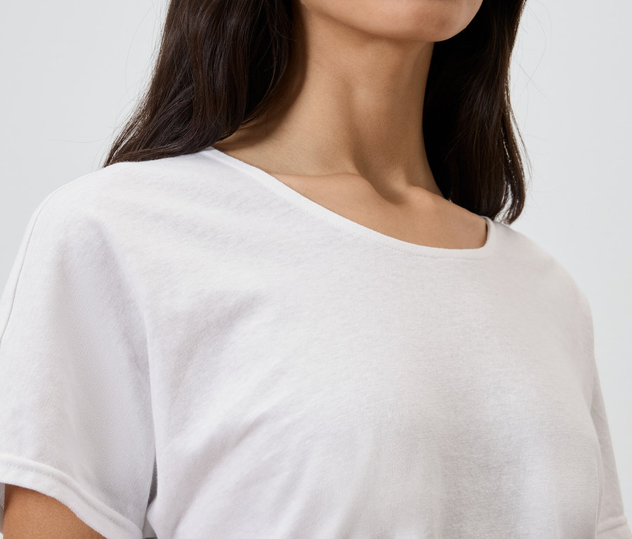 Nahaufnahme einer Frau mit dunklen Haaren, die ein weißes T-Shirt trägt.