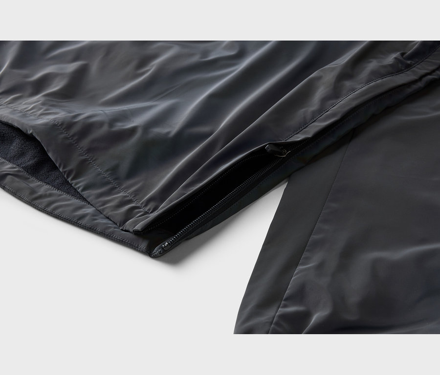Nahaufnahme einer dunkelgrauen Jacke mit teilweise geöffnetem Reißverschluss, der ein weiches, dunkles Innenfutter zeigt. Der Oberstoff ist glatt und leicht glänzend.