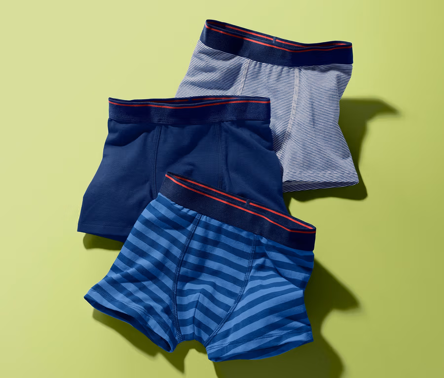 Drei Slipboxer auf grünem Hintergrund. Eine dunkelblau, eine blau gestreift und eine grau gestreift.