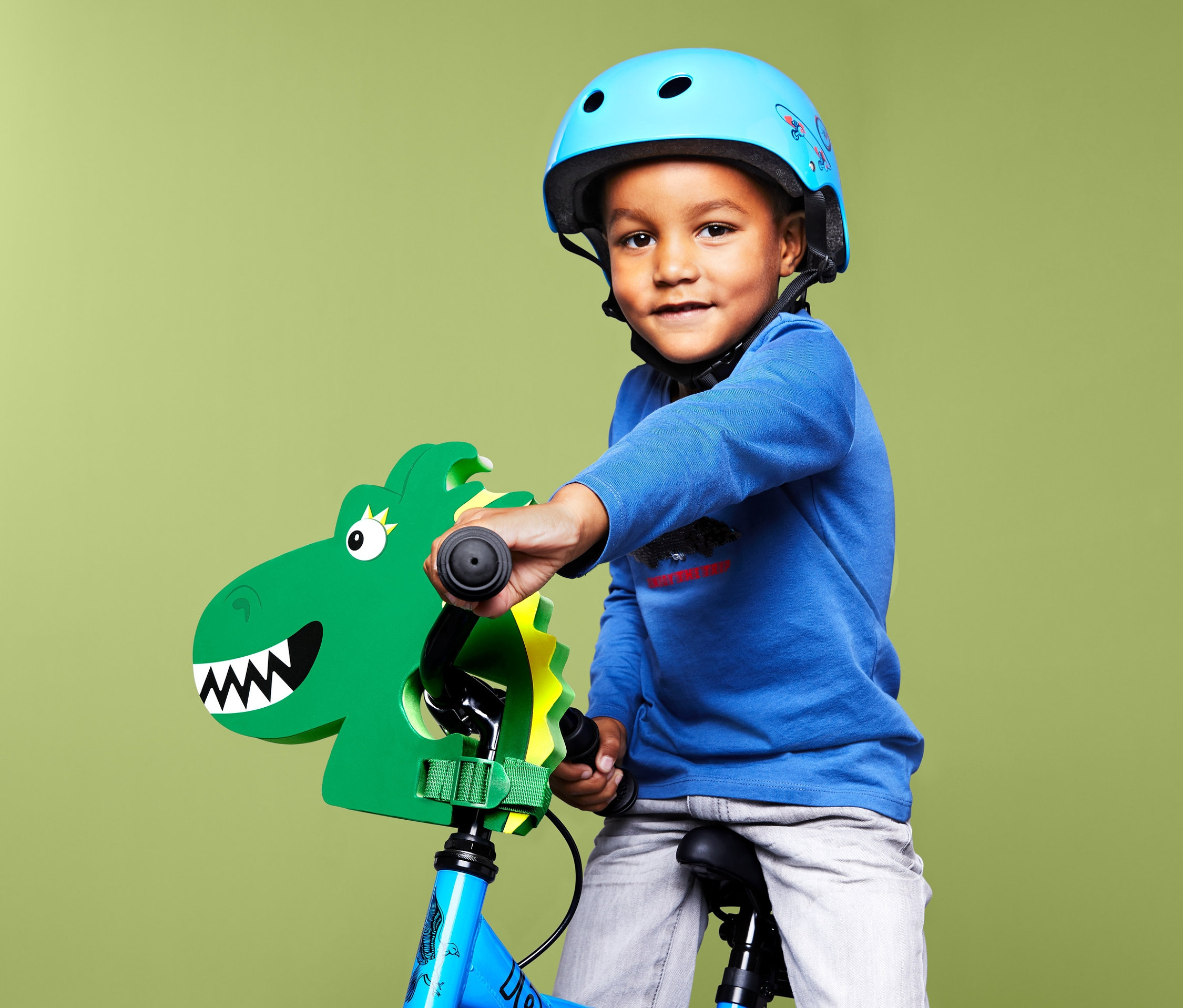 Junge mit blauem Helm auf einem Fahrrad mit Kinder-Lenkeraufsatz »Drache«.