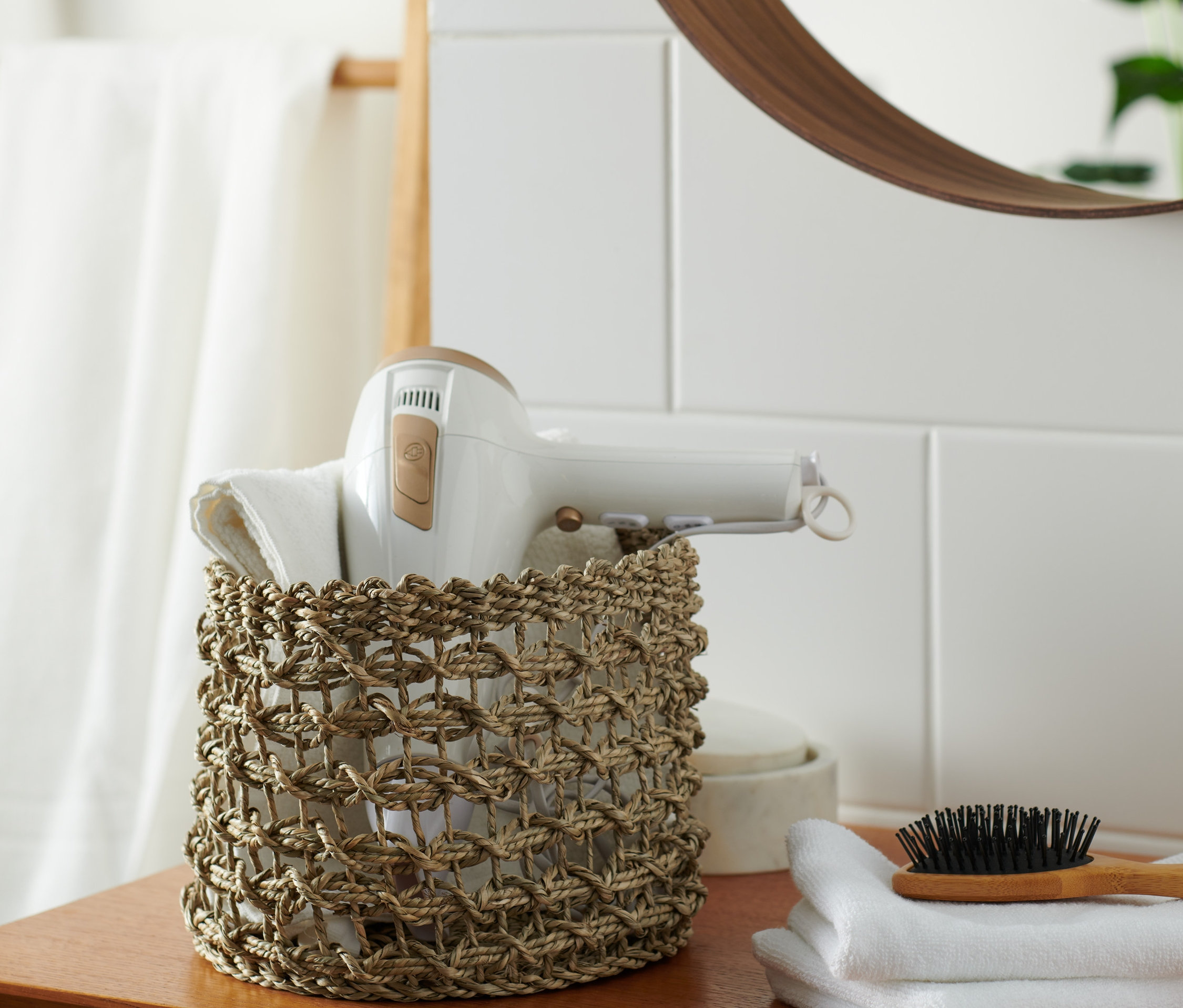 Föhn und weiße Handtücher sind in einem Aufbewahrungskorb.