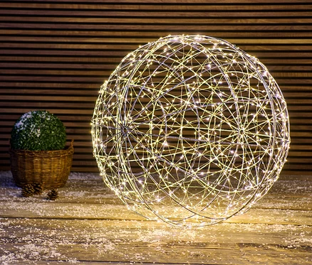 Eine große LED-Kugel steht auf einem mit Schnee bedeckten Holzboden.