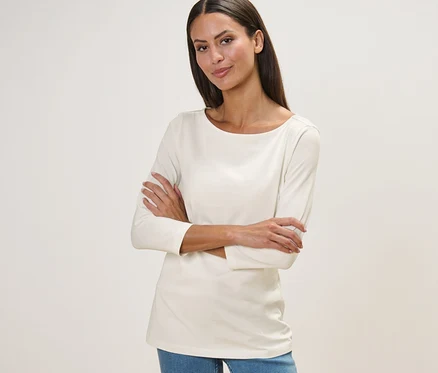 Frau steht mit verschränkten Armen und trägt ein weißes Shirt mit 3/4-Arm.