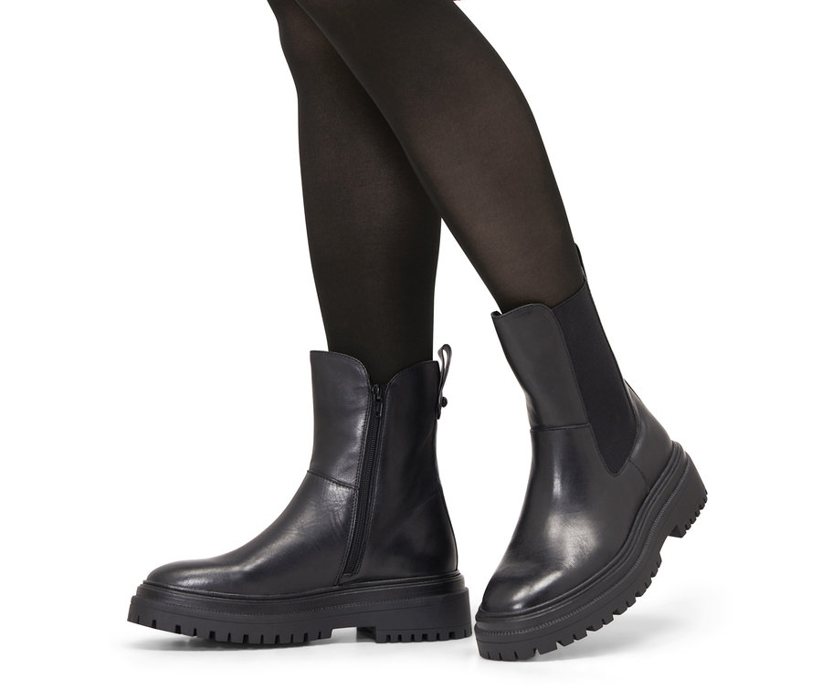 Beine in schwarzer Strumpfhose und Leder-Boots.