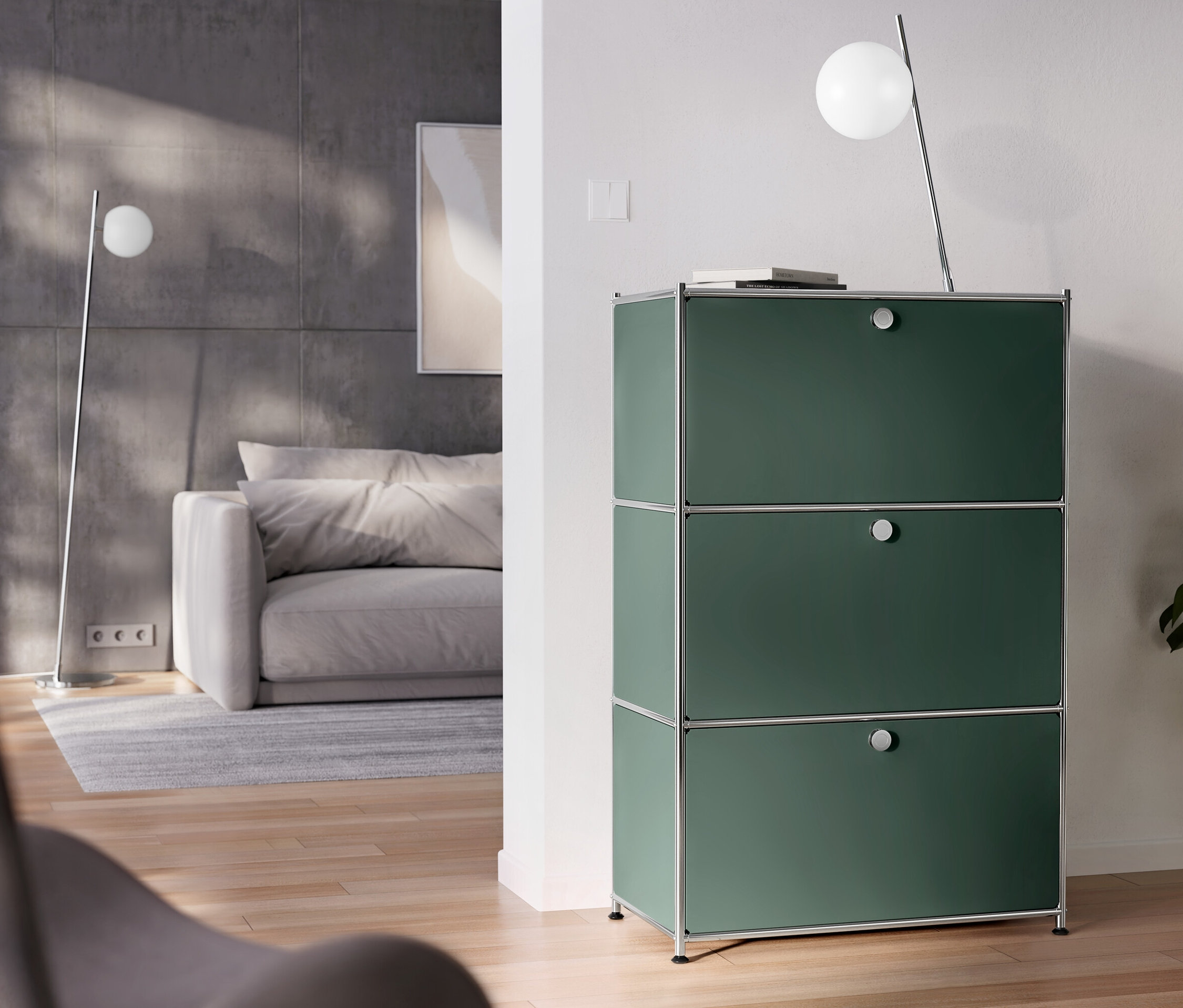 Im Raum stehen eine verchromte Tischleuchte aus Metall und eine Kommode Metall »CN3« mit 3 Klappenfächern.