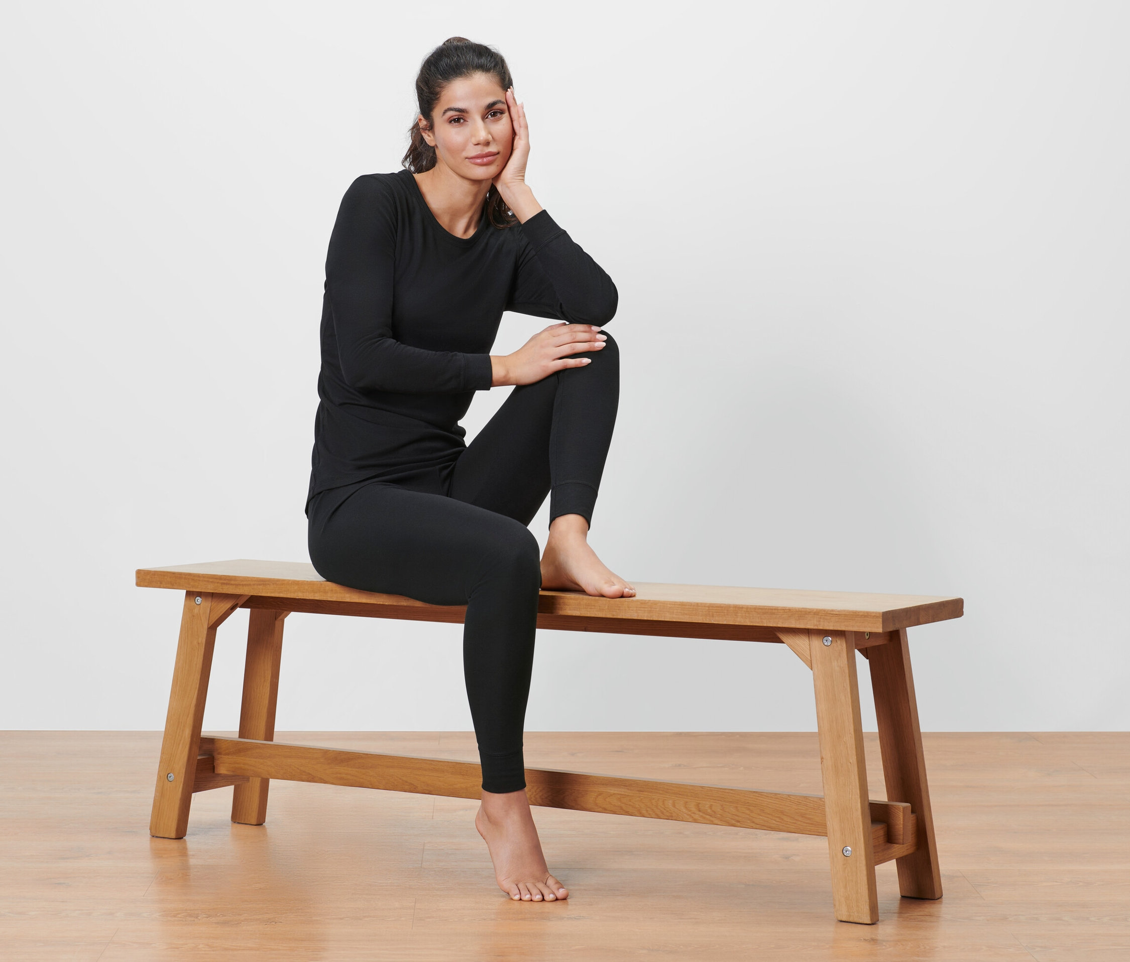 Frau sitzt in schwarzer Thermo-Funktionswäsche auf einer Bank.