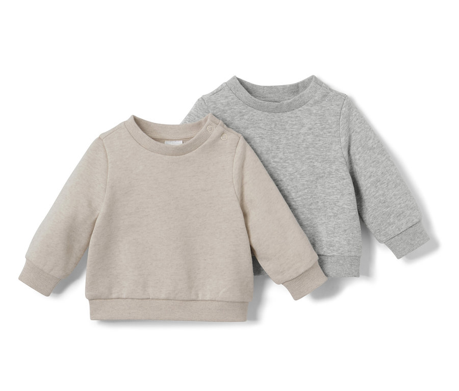 Zwei Baby-Sweatshirts mit angerauter Innenseite liegen nebeneinander.