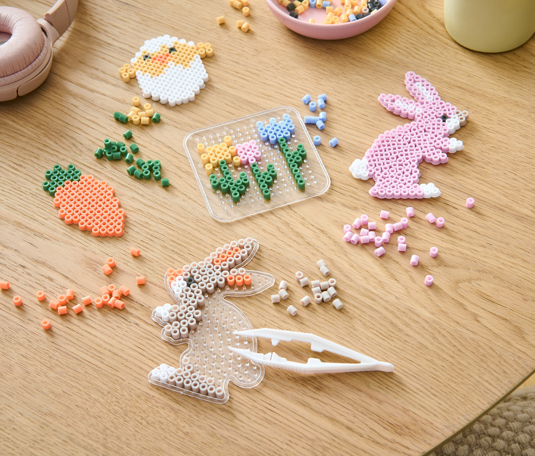 Auf einem Tisch liegen ein Bügelperlen-Bastelset und verschiedenfarbige Perlen.