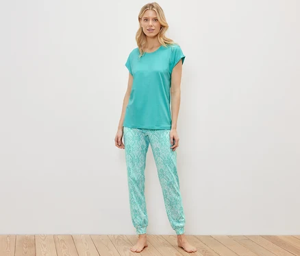 Blonde Frau steht in einem Pyjama-Set.