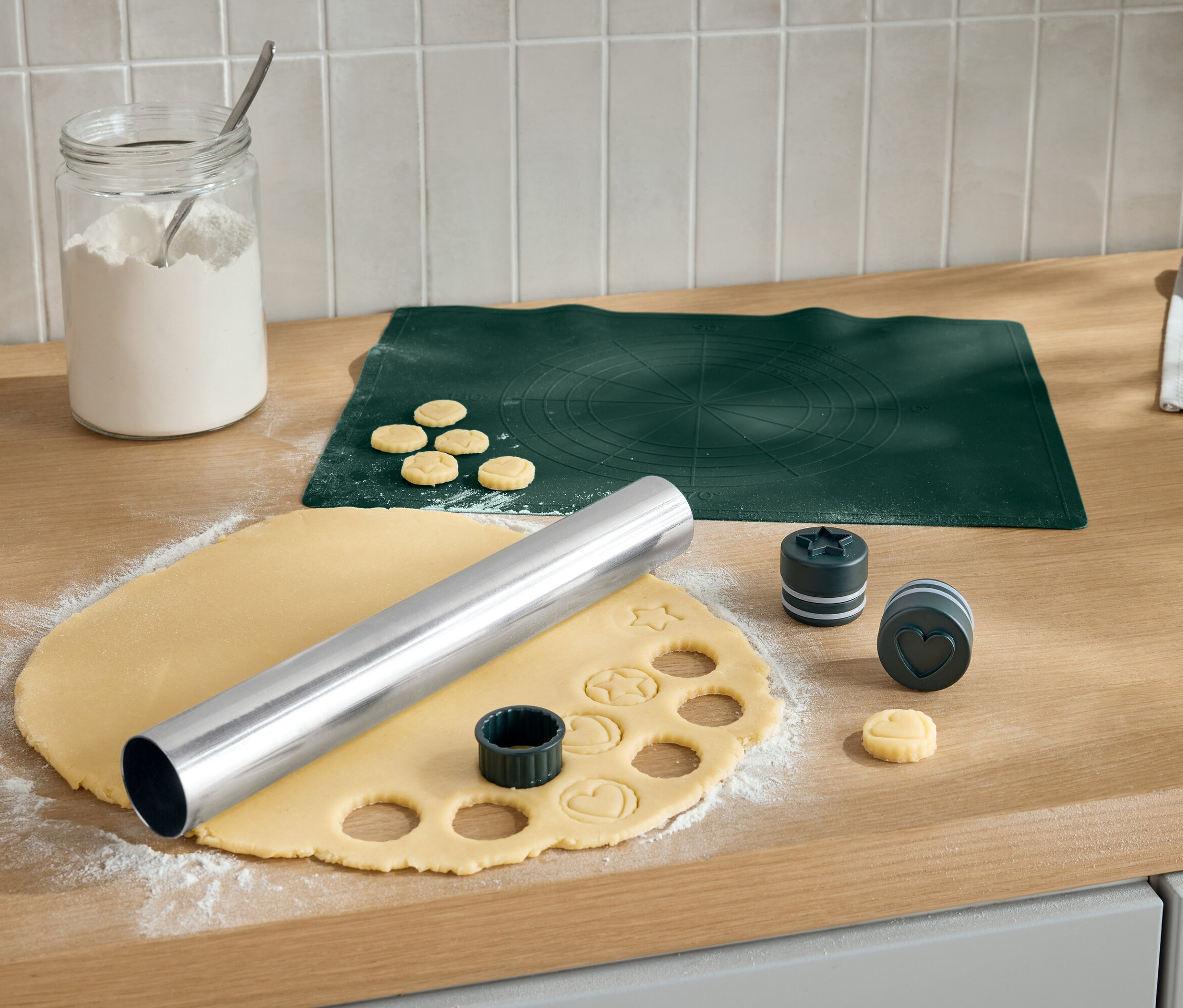 Ausstechen von Keksen auf einem Holzbrett mit einer Teigrolle und Ausstechern in verschiedenen Formen.