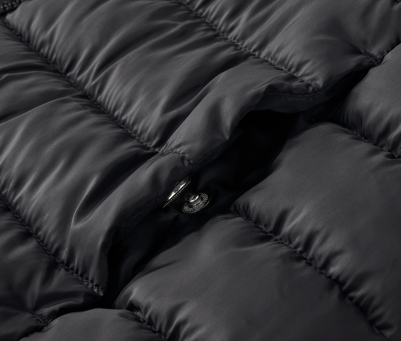 Detailaufnahme einer schwarzen Steppjacke mit Druckknopf.