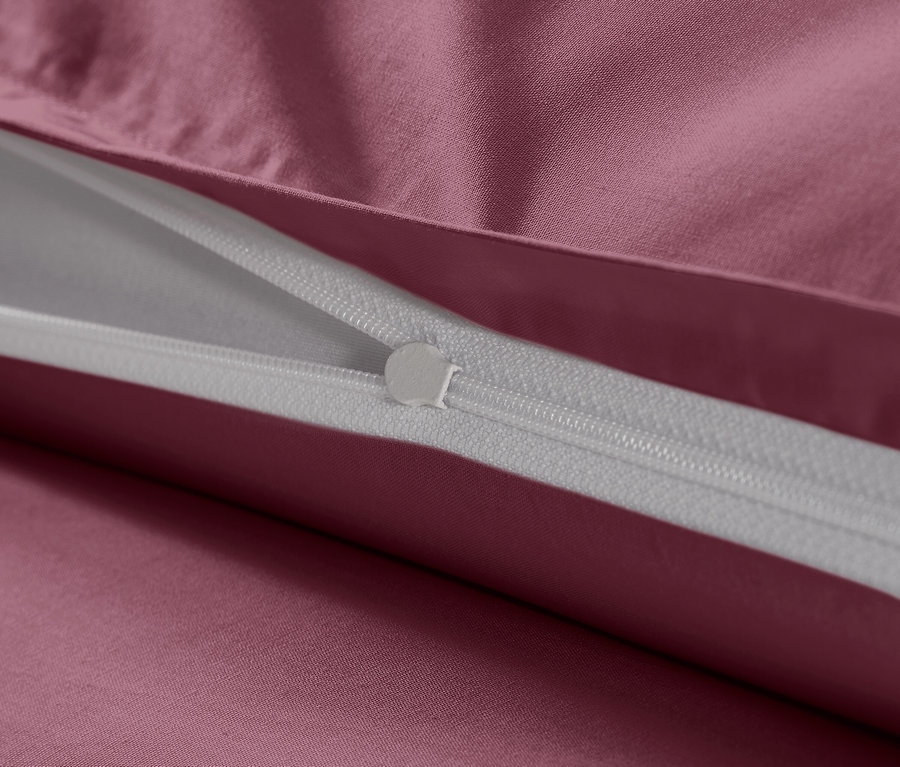 Nahaufnahme vom Reissverschluss einer beerenfarbenen Baumwollsatin-Bettwäsche in Übergrösse.