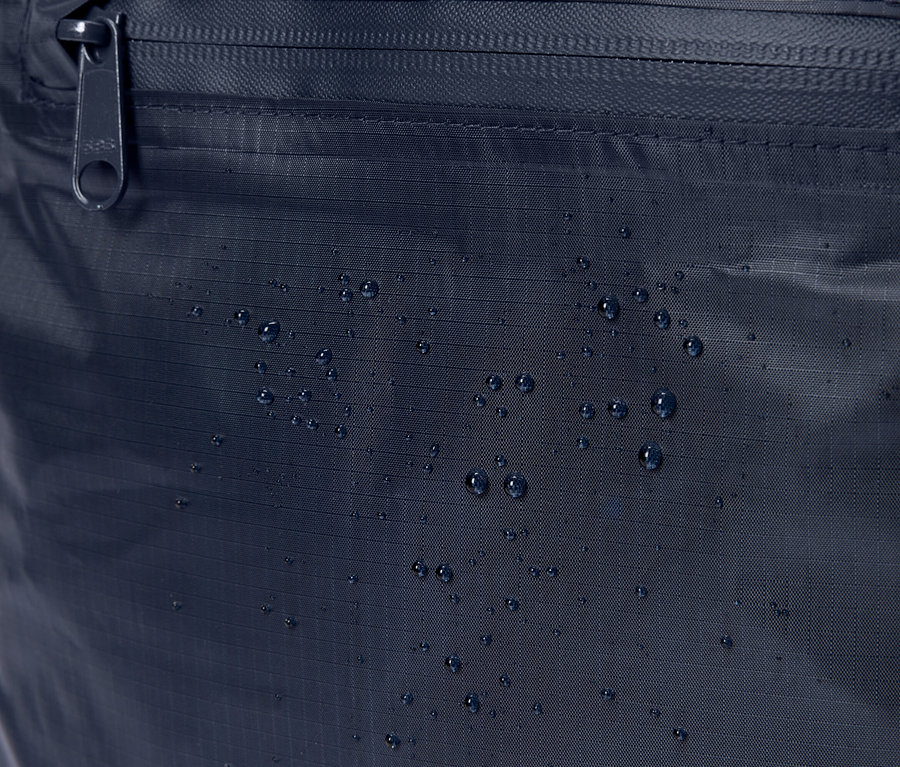Nahaufnahme einer marineblauen Stofftasche mit Reißverschluss und Wassertropfen.