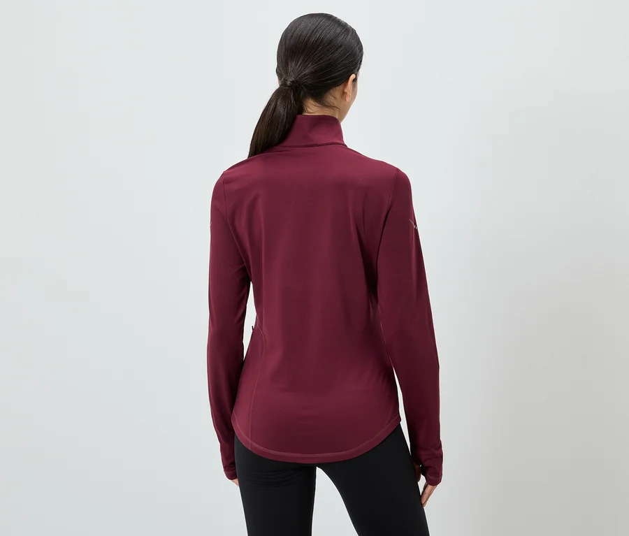 Rückansicht einer Frau mit Pferdeschwanz, die ein weinrotes Langarmshirt und schwarze Leggings trägt.