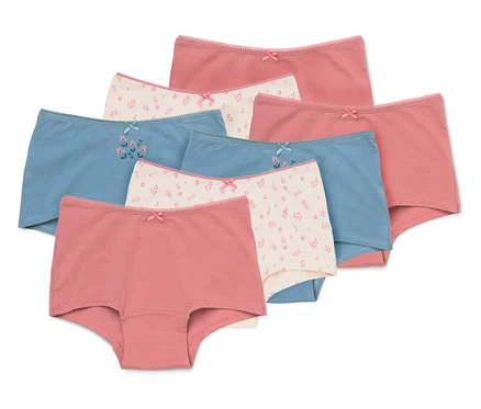 Sieben Mädchen-Pantys in verschiedenen Farben und Mustern, darunter einfarbig Rosa, Hellblau und Creme mit Blumenmuster. Jede Panty hat eine kleine Schleife vorne.