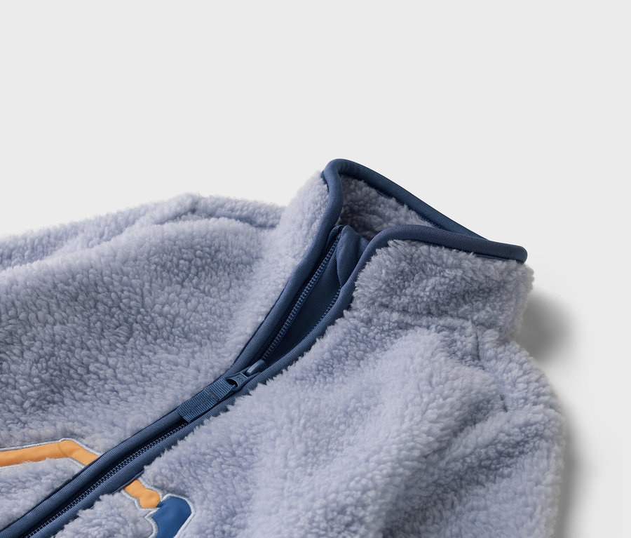 Nahaufnahme einer hellblauen Fleecejacke mit blauem Reißverschluss.
