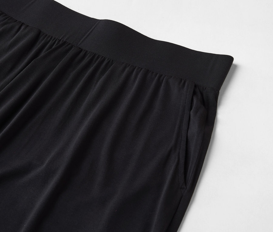 Detailaufnahme einer schwarzen Hose mit elastischem Bund und einer Tasche an der Seite.