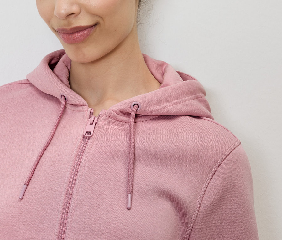 Nahaufnahme einer Frau, die einen rosa Kapuzenpullover mit Reißverschluss trägt.