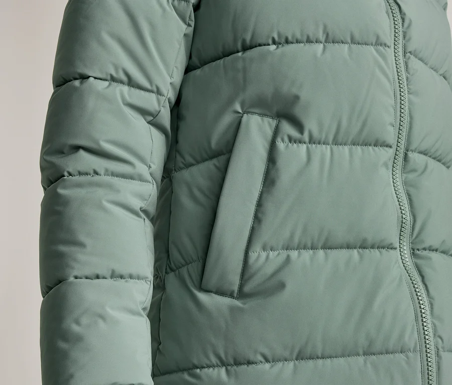 Nahaufnahme einer mintgrünen Steppjacke mit Reißverschluss und Seitentasche.