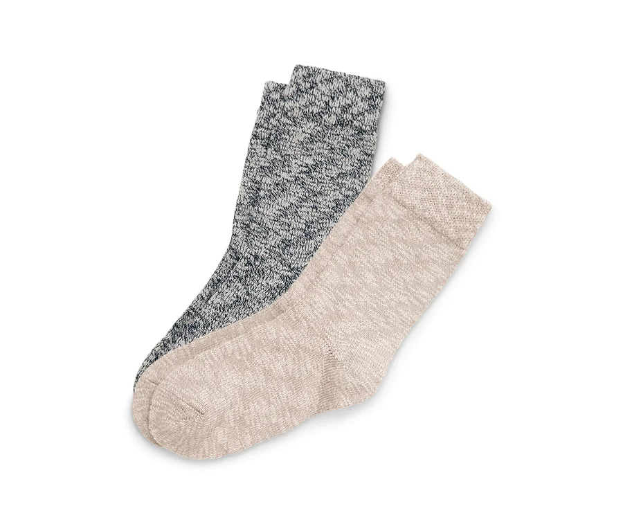 Zwei gesprenkelte Strickstrümpfe, einer dunkelgrau und einer hellbeige, liegen diagonal auf weißem Hintergrund.