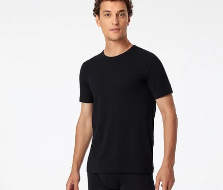 Mann trägt ein schwarzes SCHIESSER T-Shirt und schwarze Boxershorts vor weißem Hintergrund.