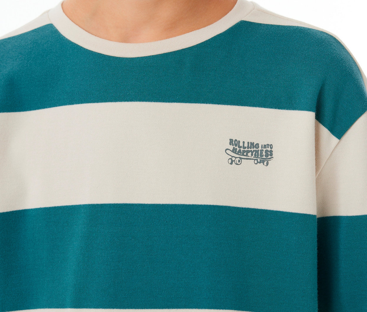 Person trägt einen SCHIESSER Kinder-Interlock-Pyjama mit türkis-cremefarbenen Streifen und Skateboard-Grafik 'ROLLING INTO HAPPINESS'.