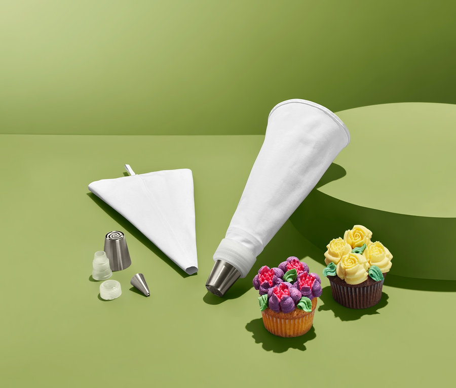 Spritztüllen-Set mit zwei dekorierten Cupcakes auf grünem Hintergrund.