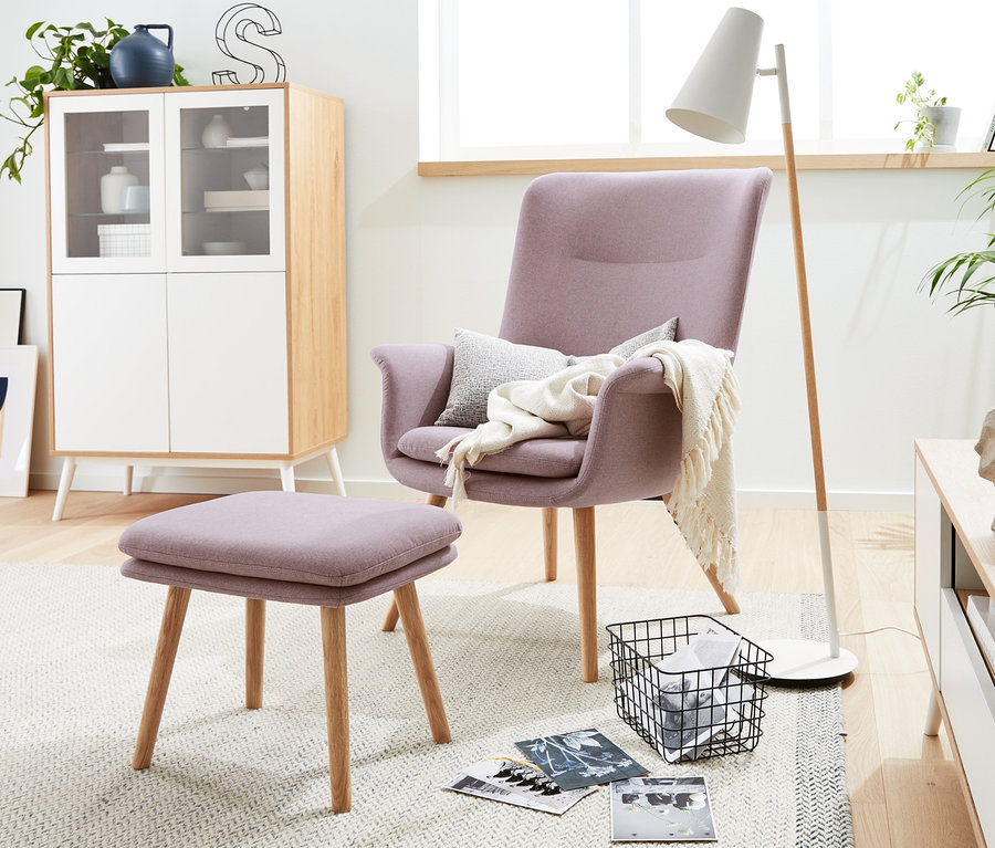 Ein lila Sessel mit Hocker steht in einem Wohnzimmer.