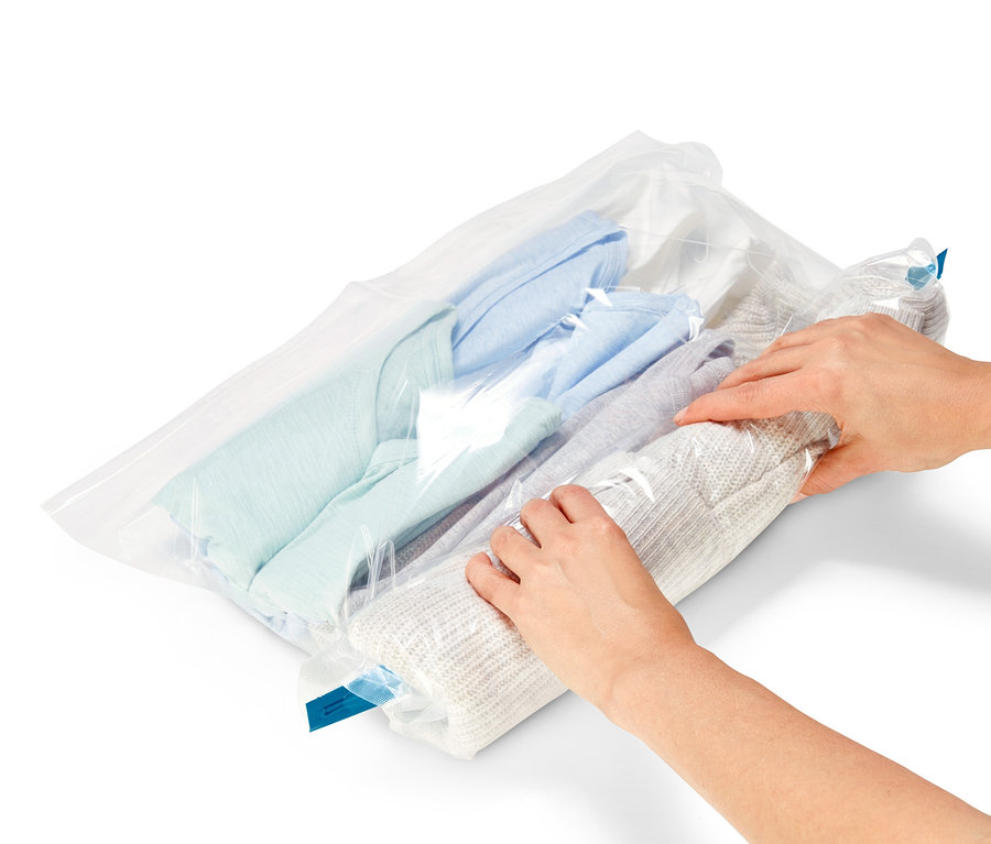 Hände rollen Pullover in 3 Vakuum-Reisebeutel.