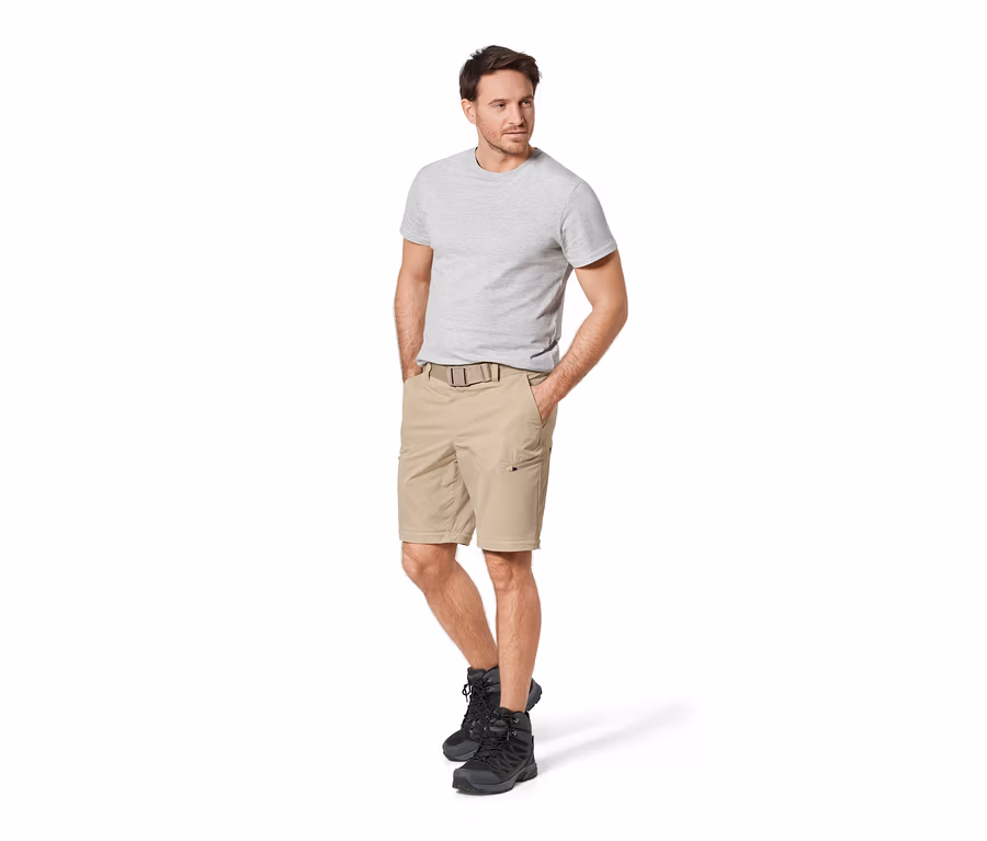 Mann steht mit Händen in den Taschen einer beigen 2-in-1-Funktionshose.