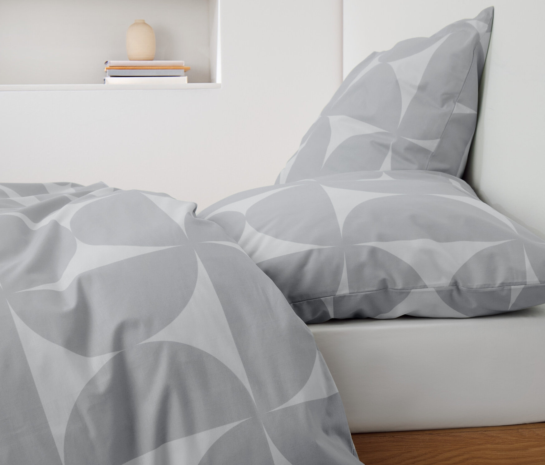 Detailansicht grauer Renforcé-Bettwäsche mit Muster auf einem Bett.