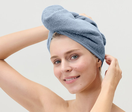 Frau fixiert Turban-Handtuch, hellblau, auf ihrem Kopf.